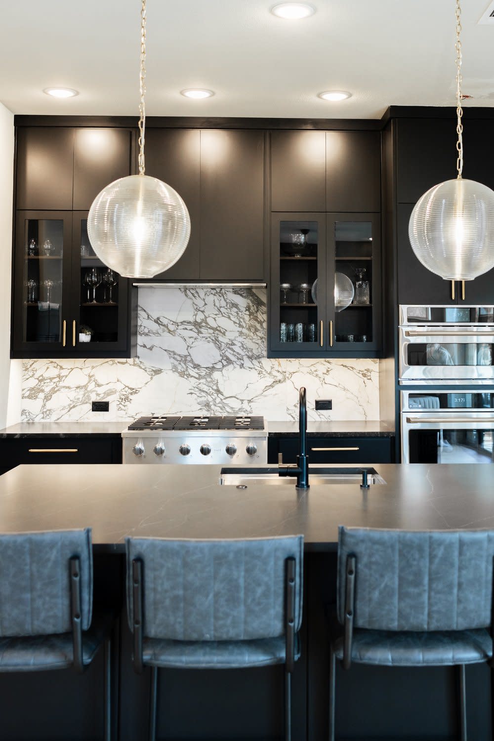 A stylish kitchen featuring black cabinets and luxurious marble countertops