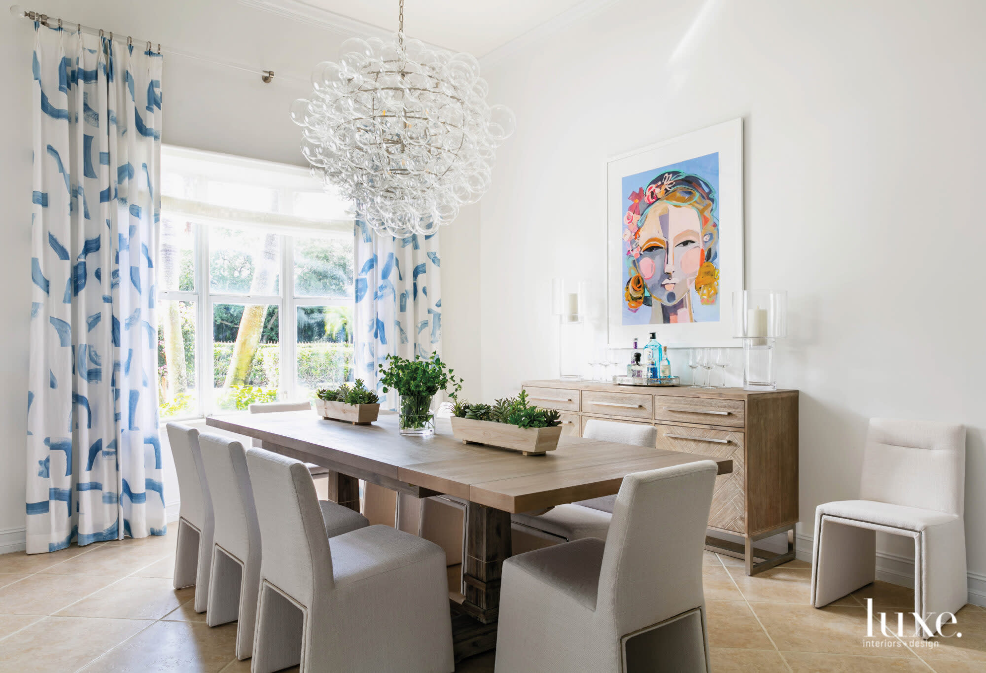 dining room with blue and white curtains and vibrant wall portrait