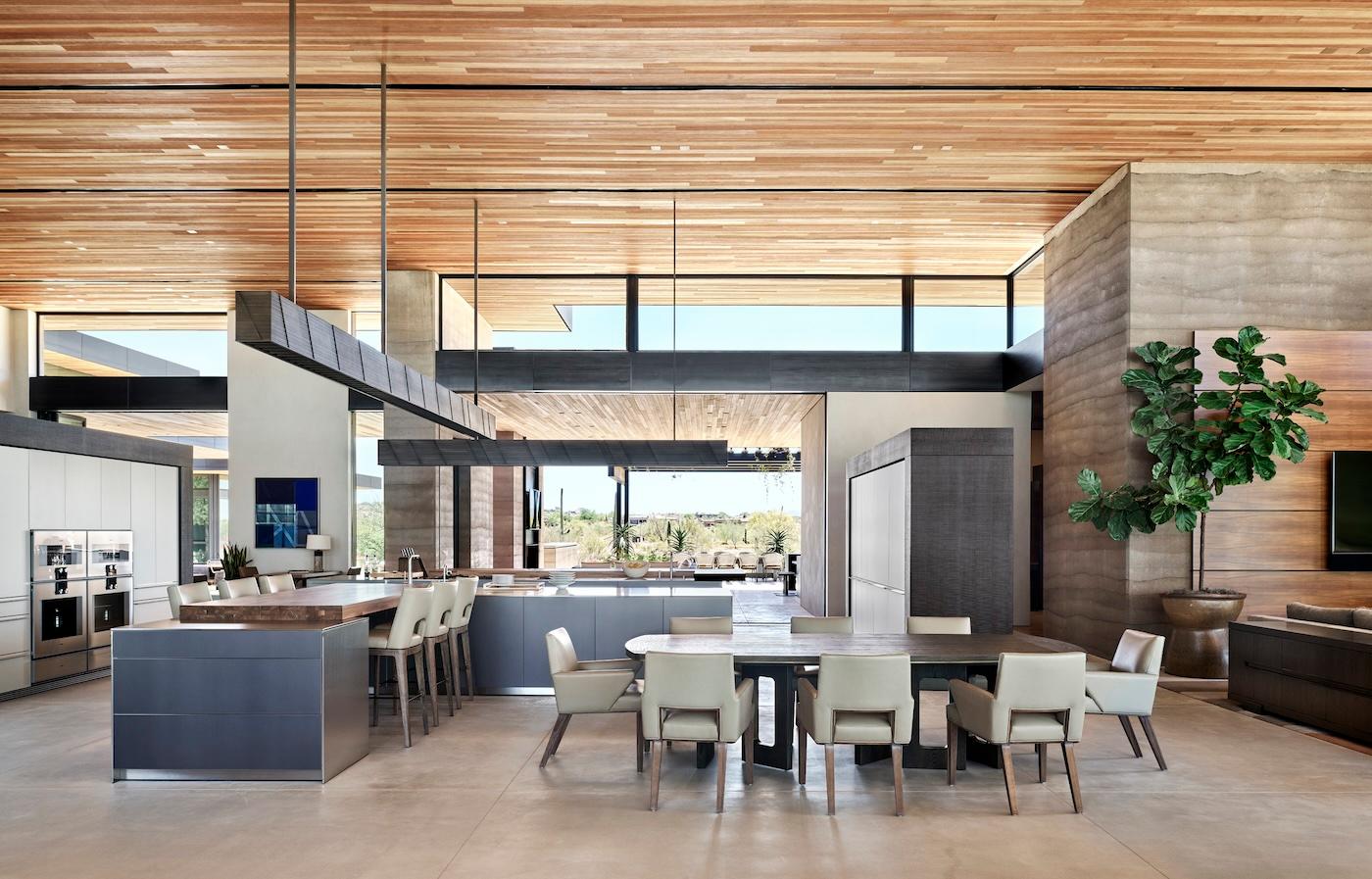 Spacious modern kitchen and dining area with sleek wooden ceiling, large windows, neutral tones, and open floor plan. Includes contemporary furniture and decor.
