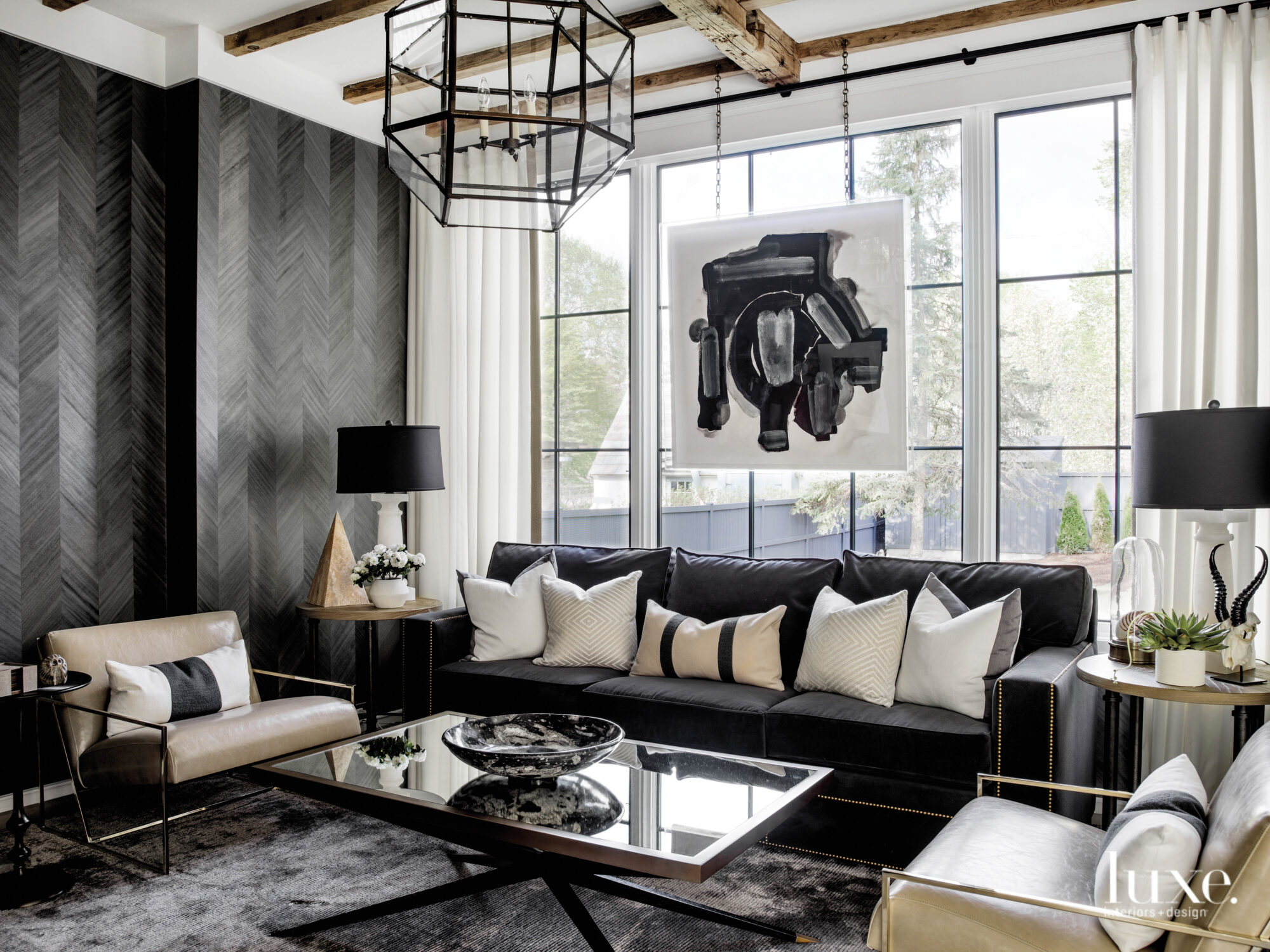 The study has dark charcoal wood-grained wallpaper, a dark gray couch and a dark gray rug. A painting by Zoe Bios Creative hangs in the window.