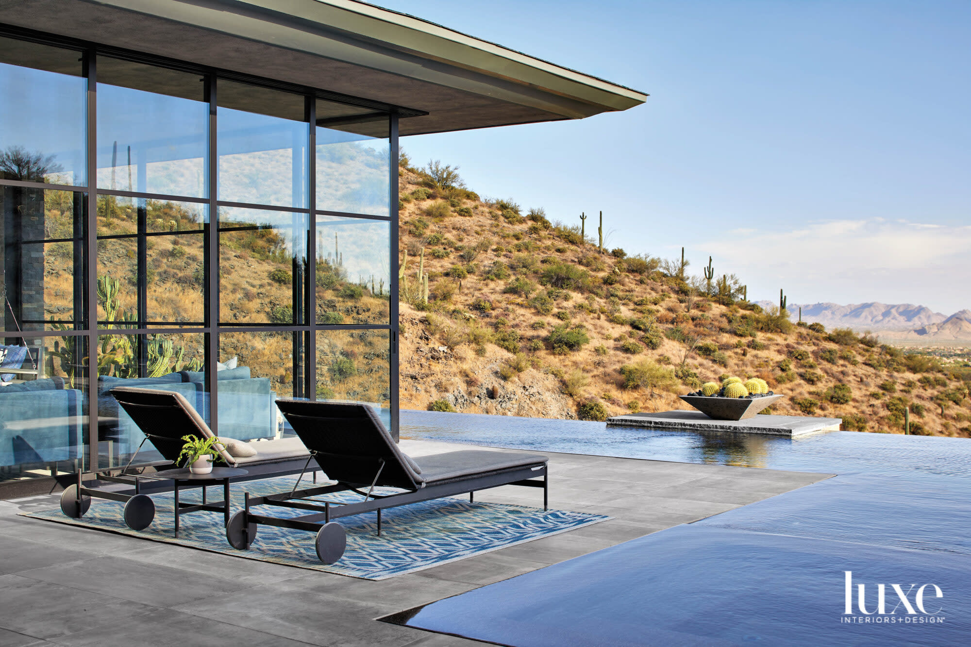 Two lounge chairs on the patio overlook an infinity pool and the mountains beyond.