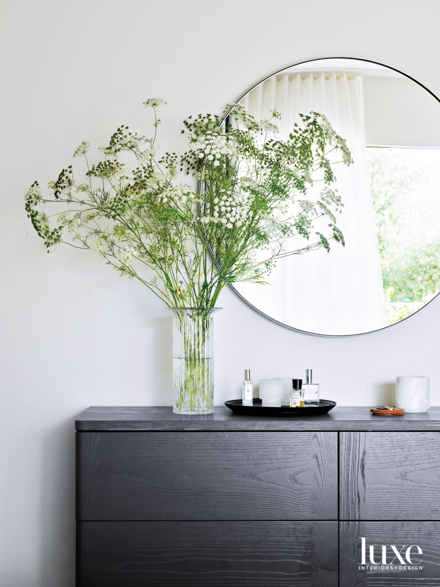 round mirror and floral arrangement in bedroom