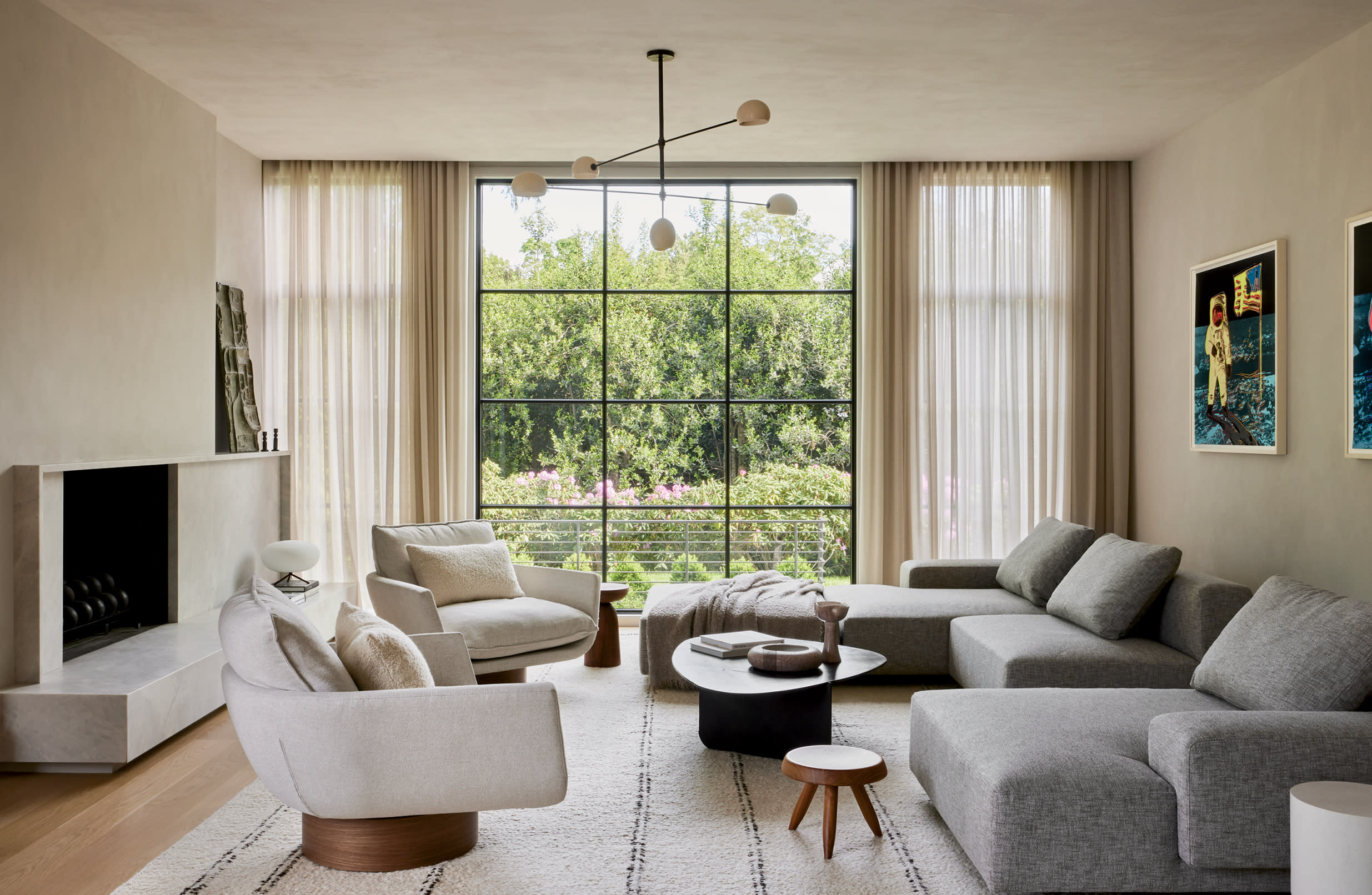 living room with Andy Warhol prints above a grey sectional and white swivel armchairs