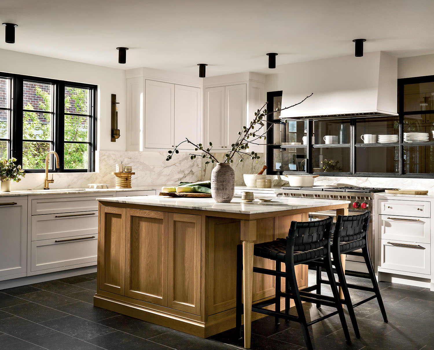 Modern kitchen with a wooden island, white cabinets, and black bar stools.