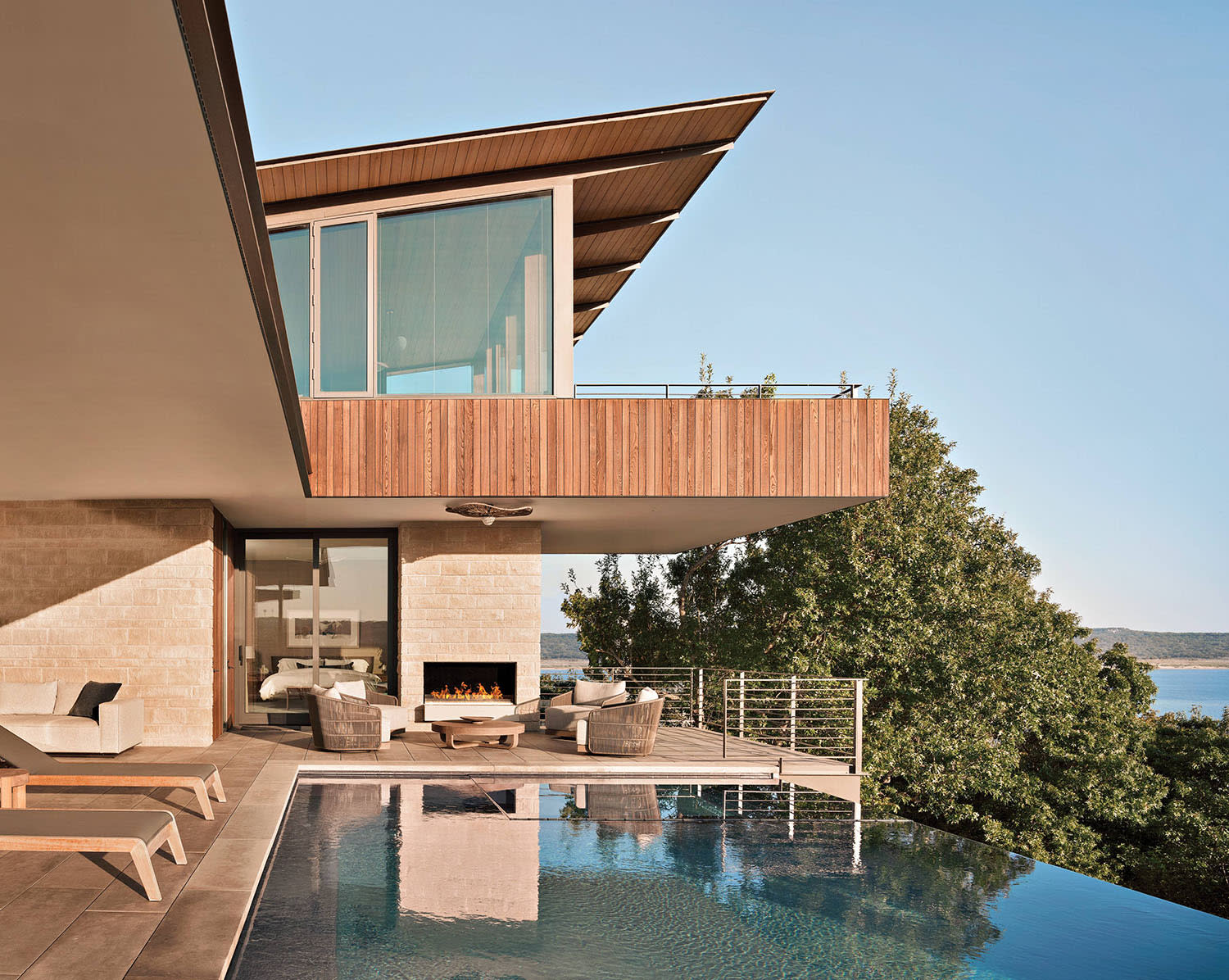 outdoor fireplace and deck beside an infinity pool