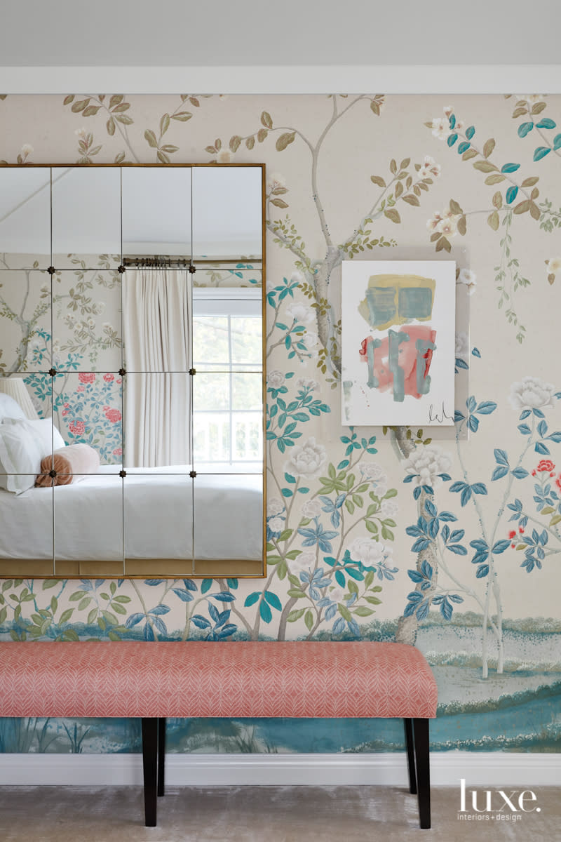 Along one wall in the master bedroom is a pink bench and paned mirror.
