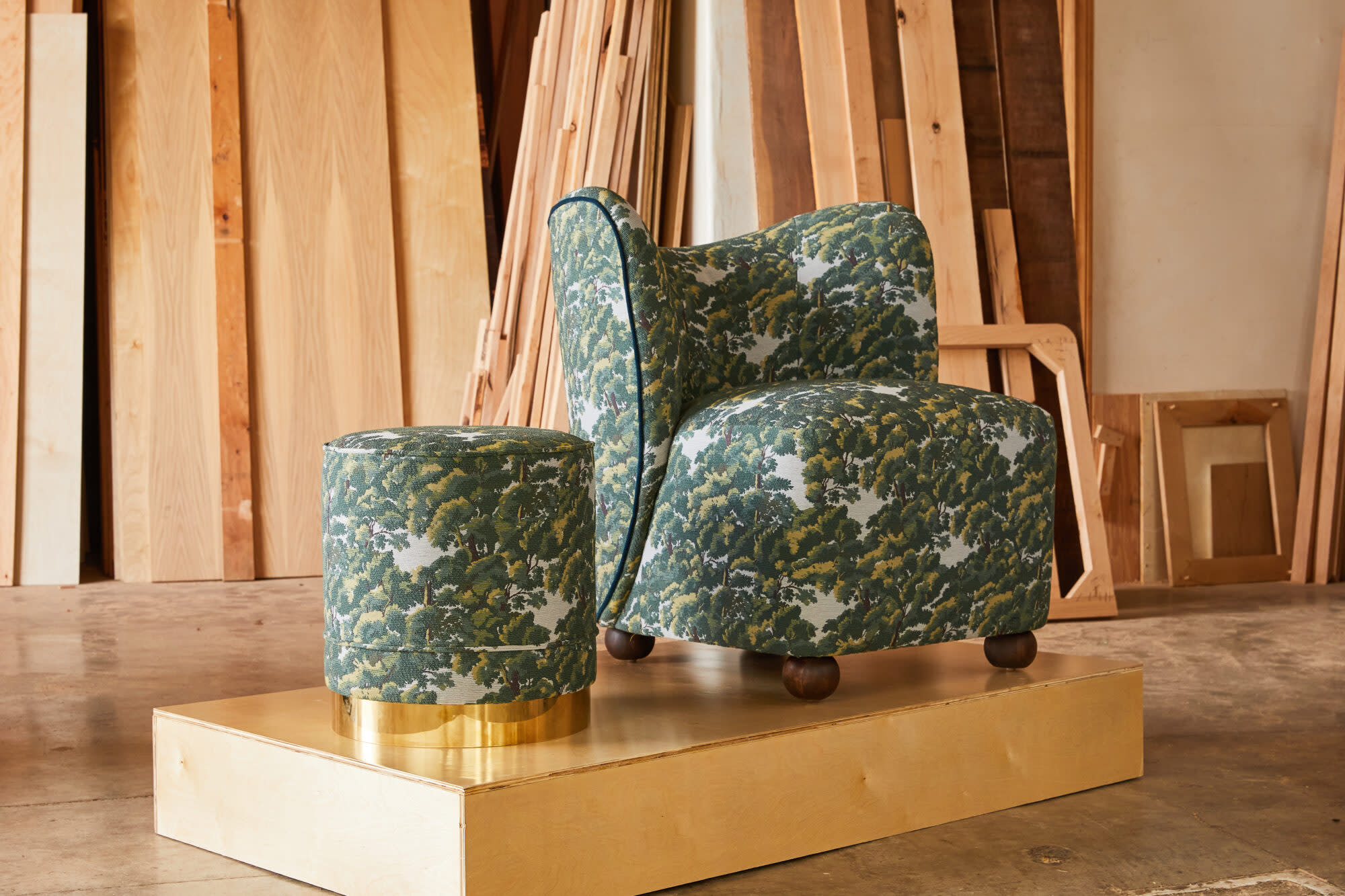 Chair and stool with oak tree-patterned upholstery sitting upon a platform