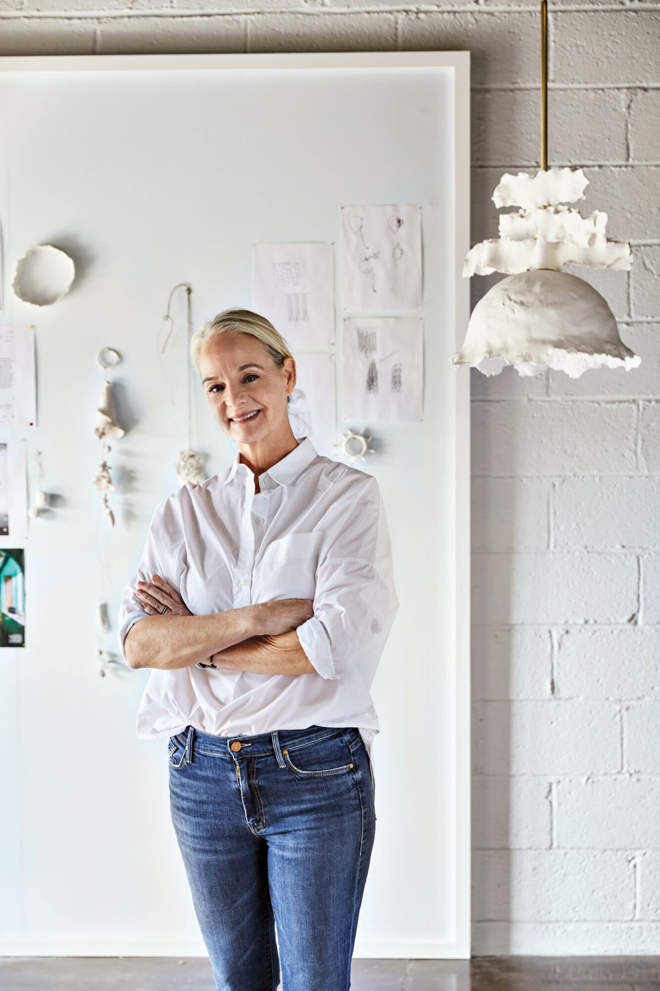 Woman standing in white room with arms crossed