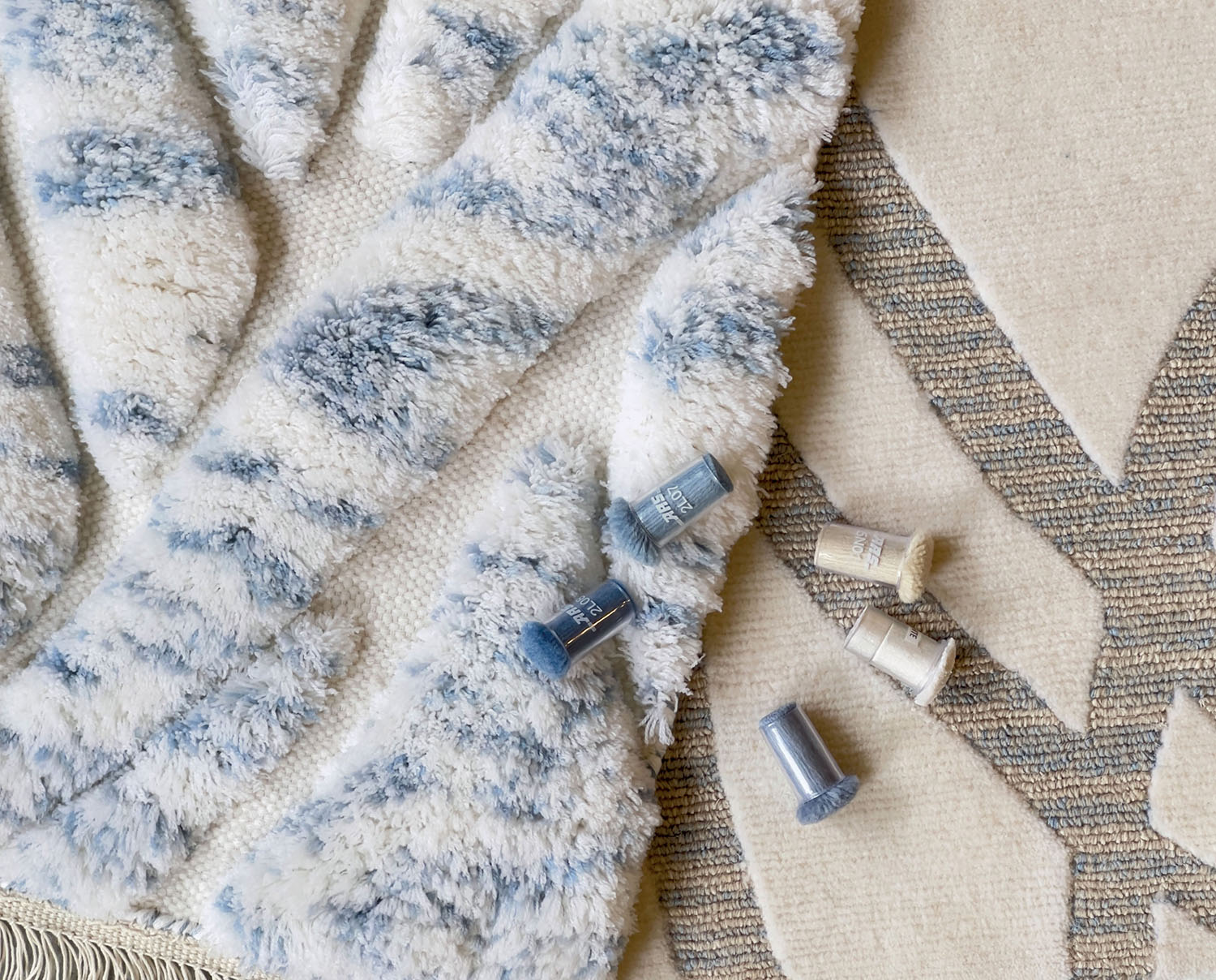A blue-and-white patterned rug and a white-and-gray patterned rug layered on top of one another.
