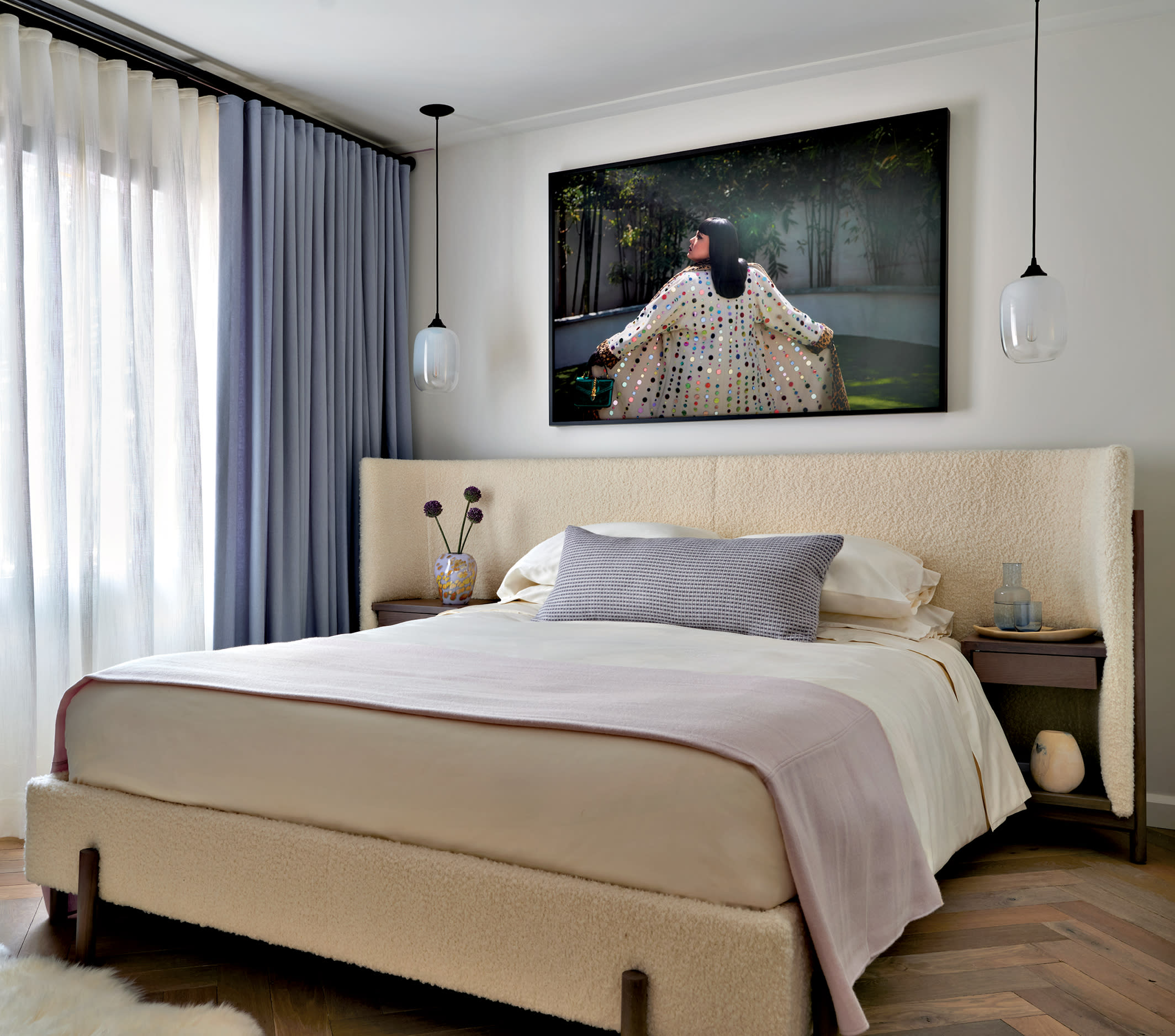 contemporary bedroom with a boucle curved headboard and wood flooring