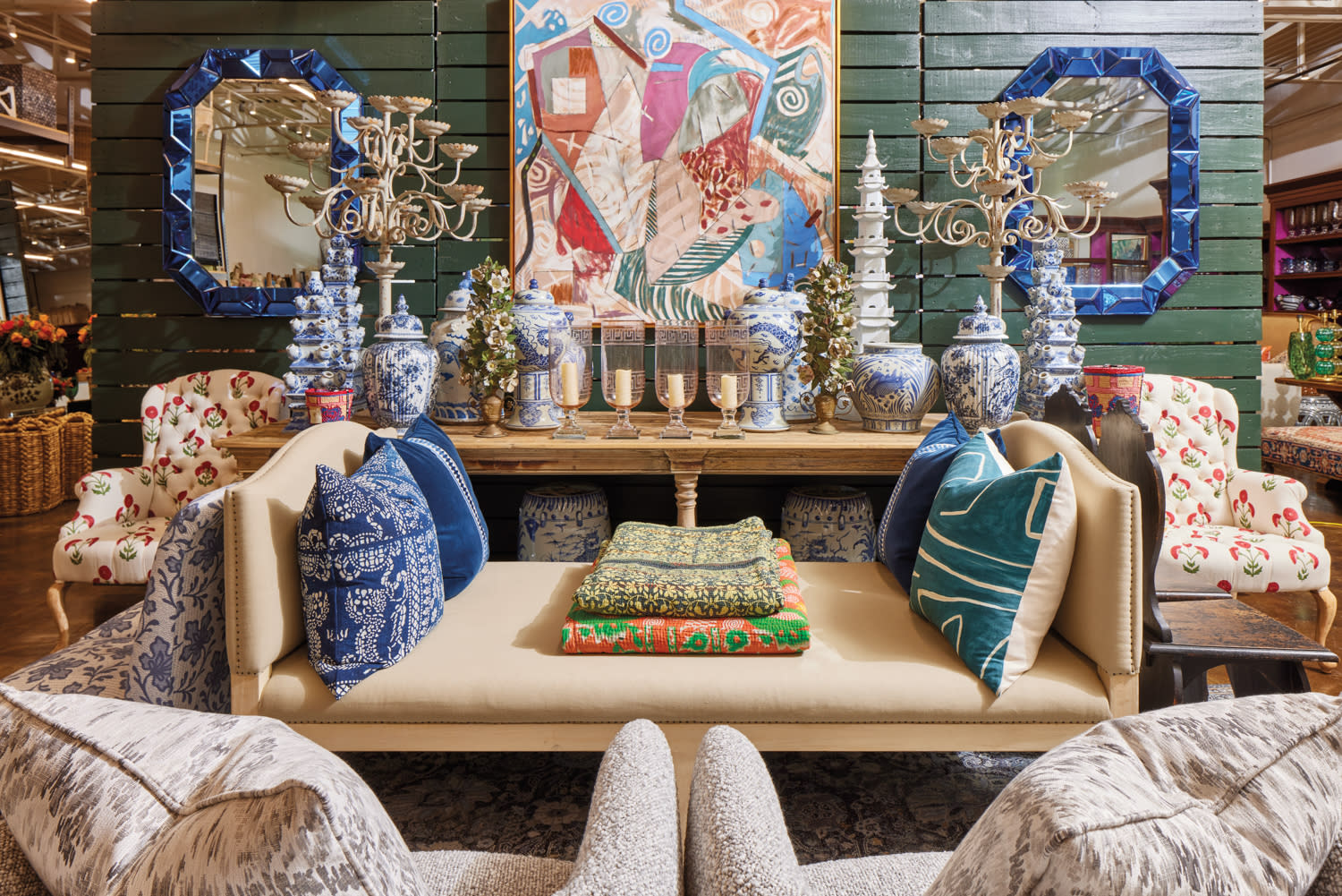 Curated showroom vignette of seating, pillows, chinoiserie vessels and mirrors.