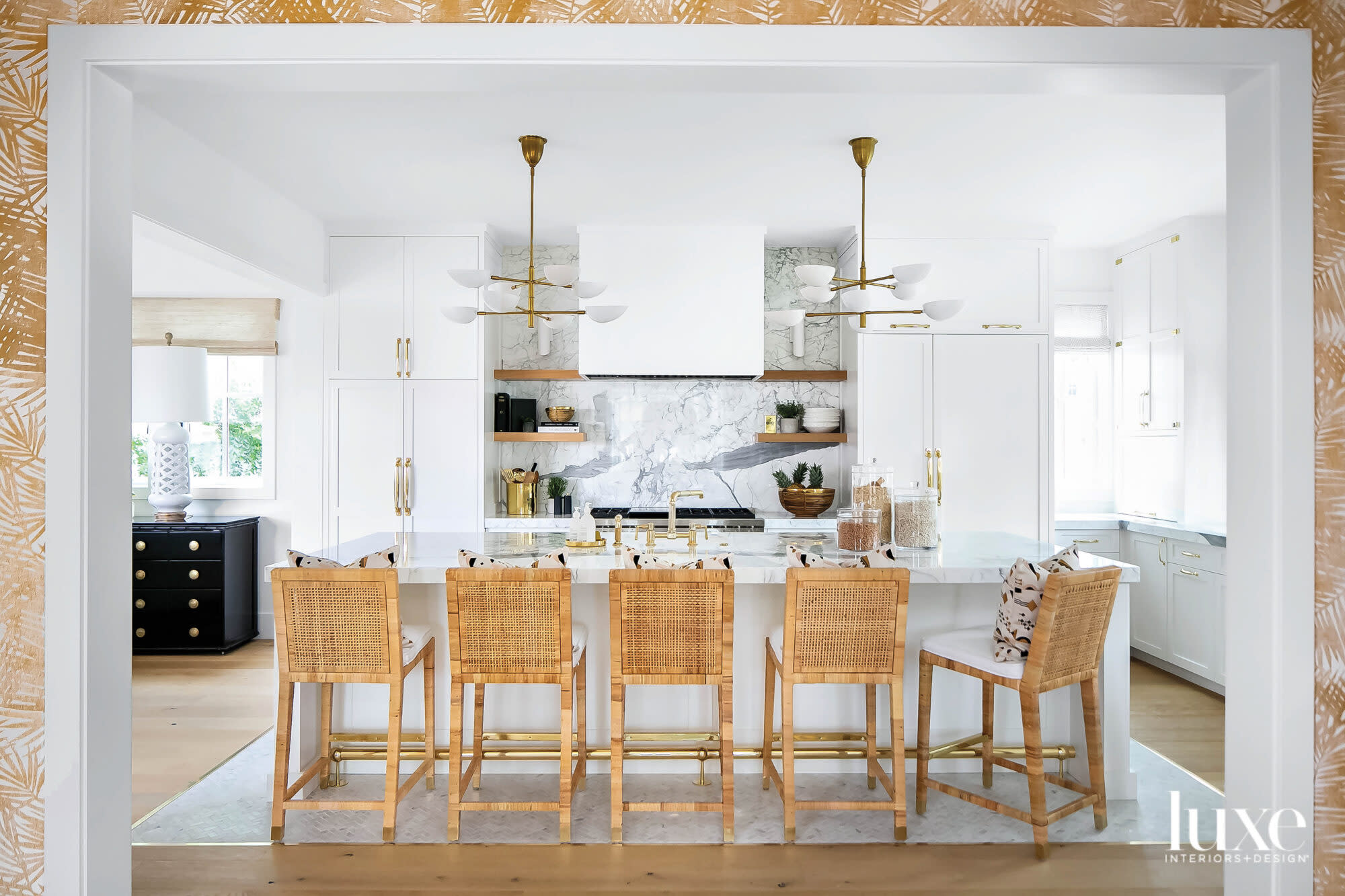 Kitchen island with row of bar chairs and lights above