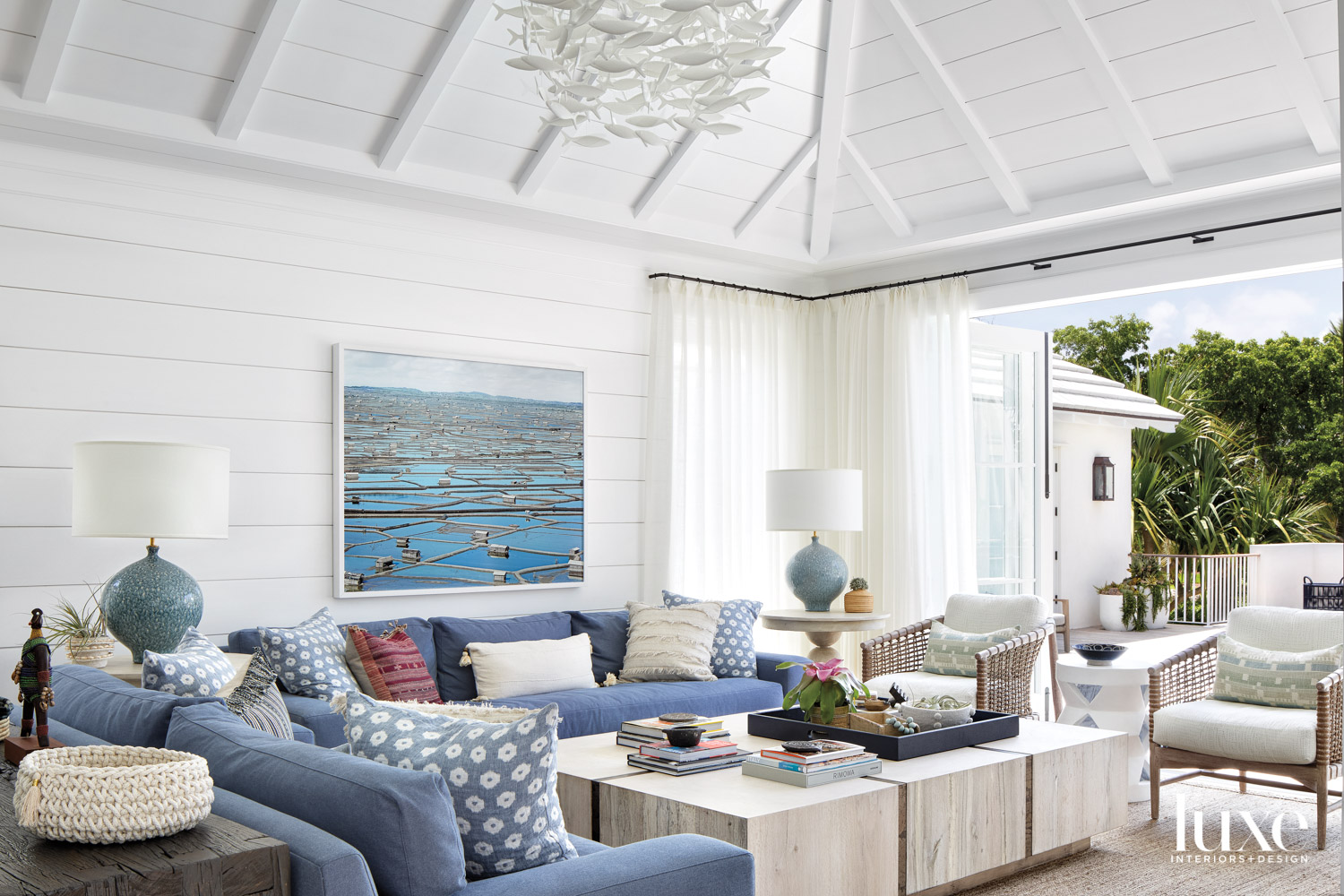 white living area with shiplap, beamed ceilings, blue sofas and natural materials