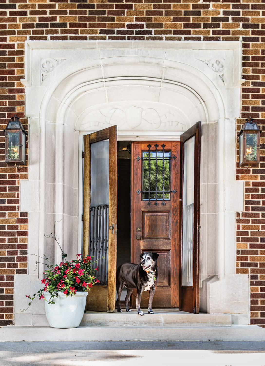 Brick and limestone residence with brown wood front doors and a pet dog