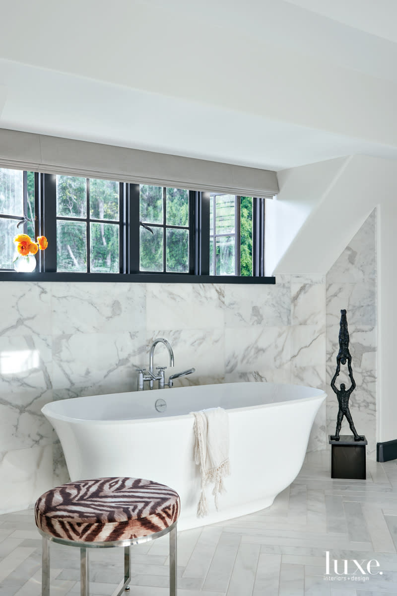 master bathroom with stand alone tub and sculpture, tile flooring and marble walls