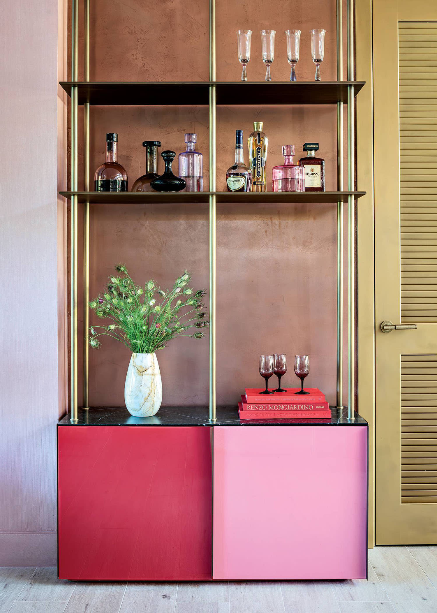 pink and red bookcase used as a home bar