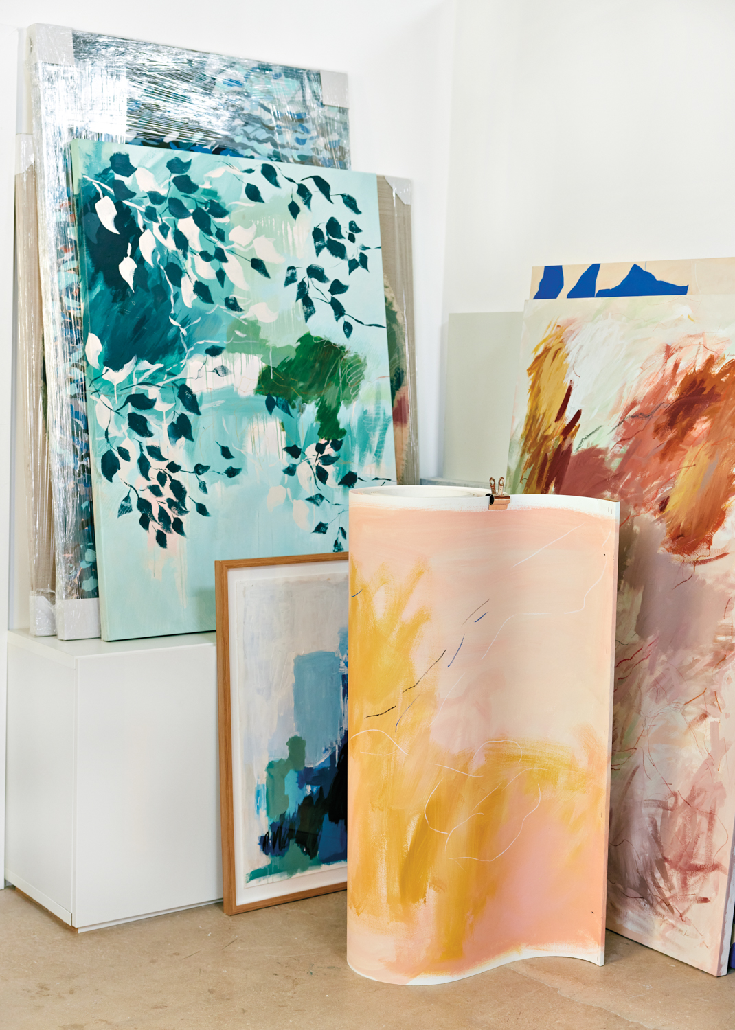 group of paintings by Veronica Pasman in her white-walled studio in Liberty City