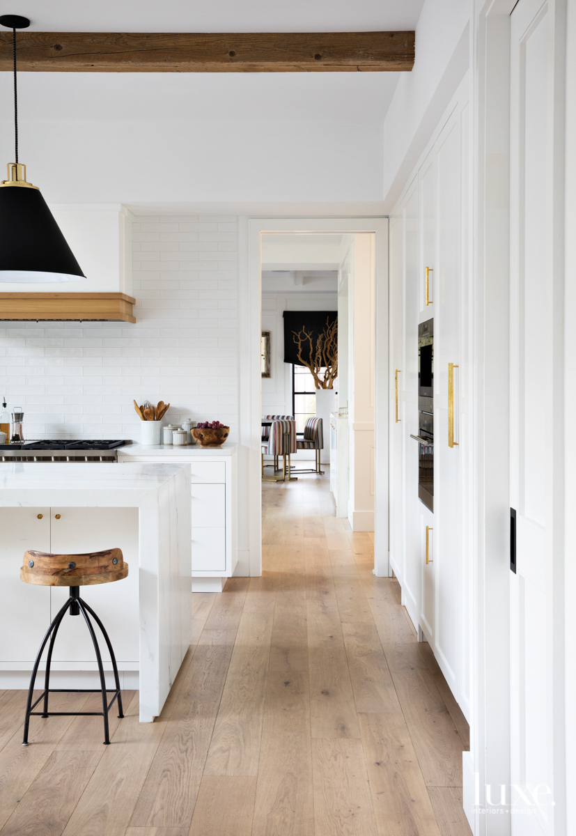 kitchen featuring rustic beams and wood detailing with stools and matte black and brass pendants