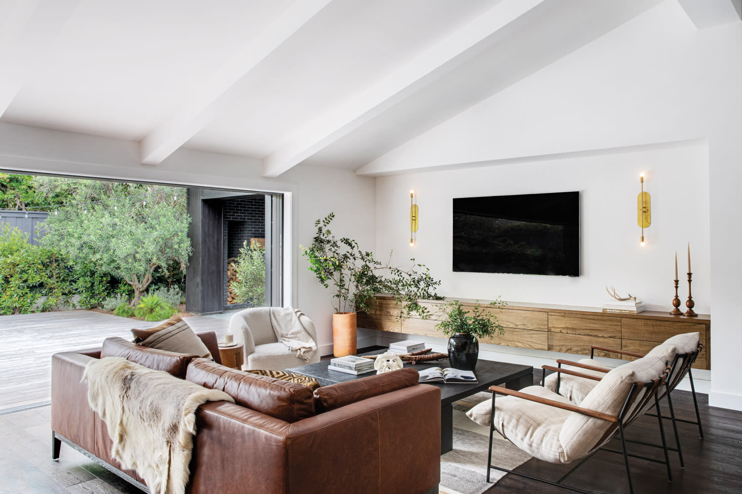 living room with leather sofa, armchairs, swivel chair, black coffee table and floating wood vanity