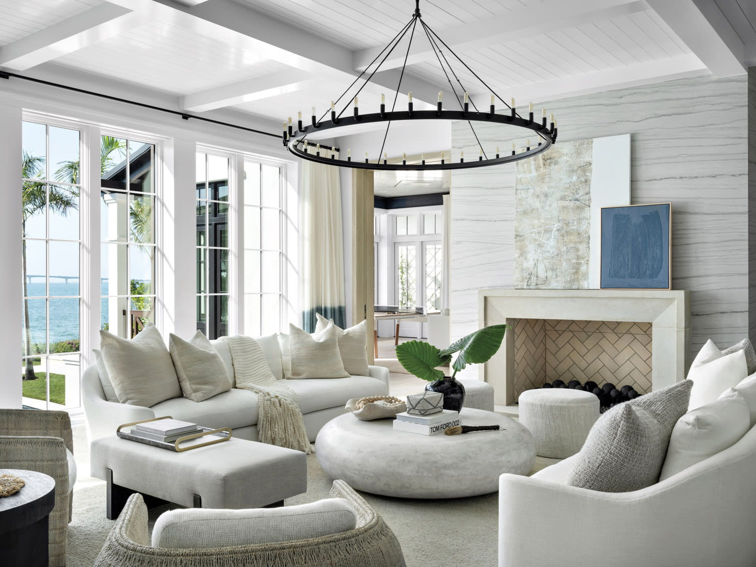 living room with white sofas, round stone coffee table, gray wall, fireplace and round black chandelier