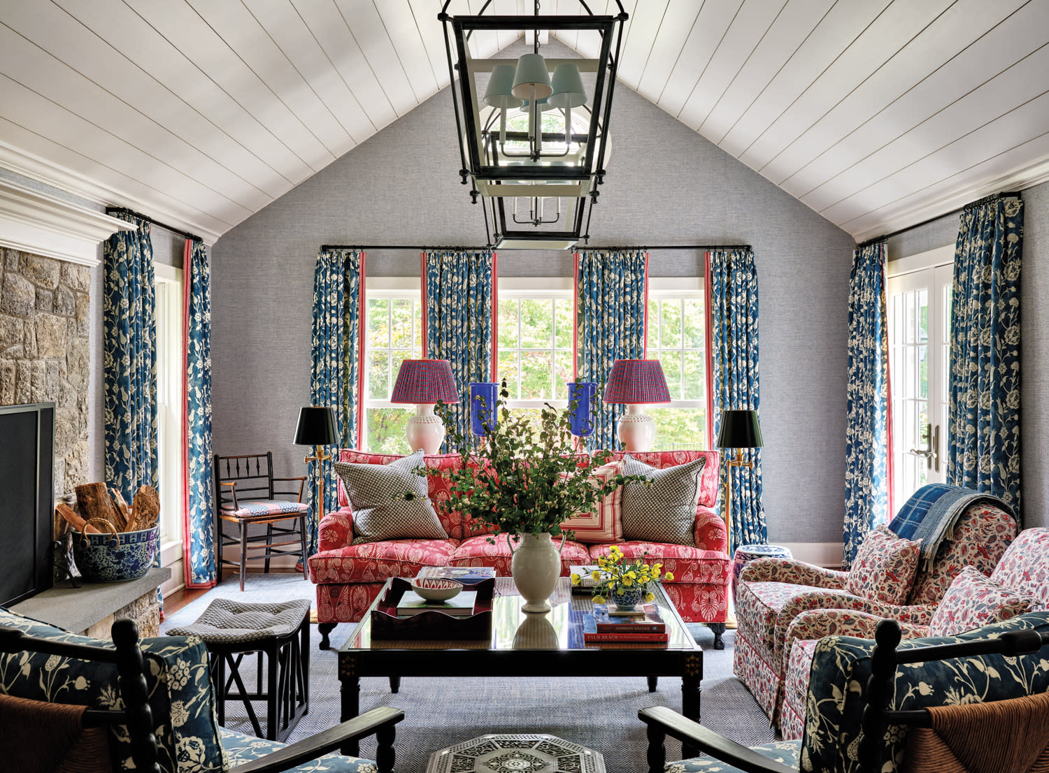 family room with red sofa, brown coffee table, blue patterned drapes and lantern-style chandelier