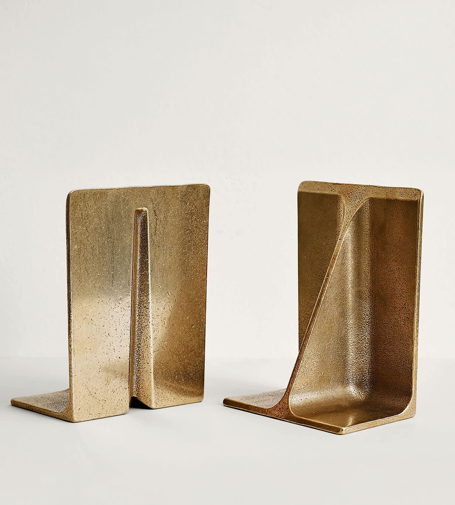 A pair of brass bookends standing side by side.