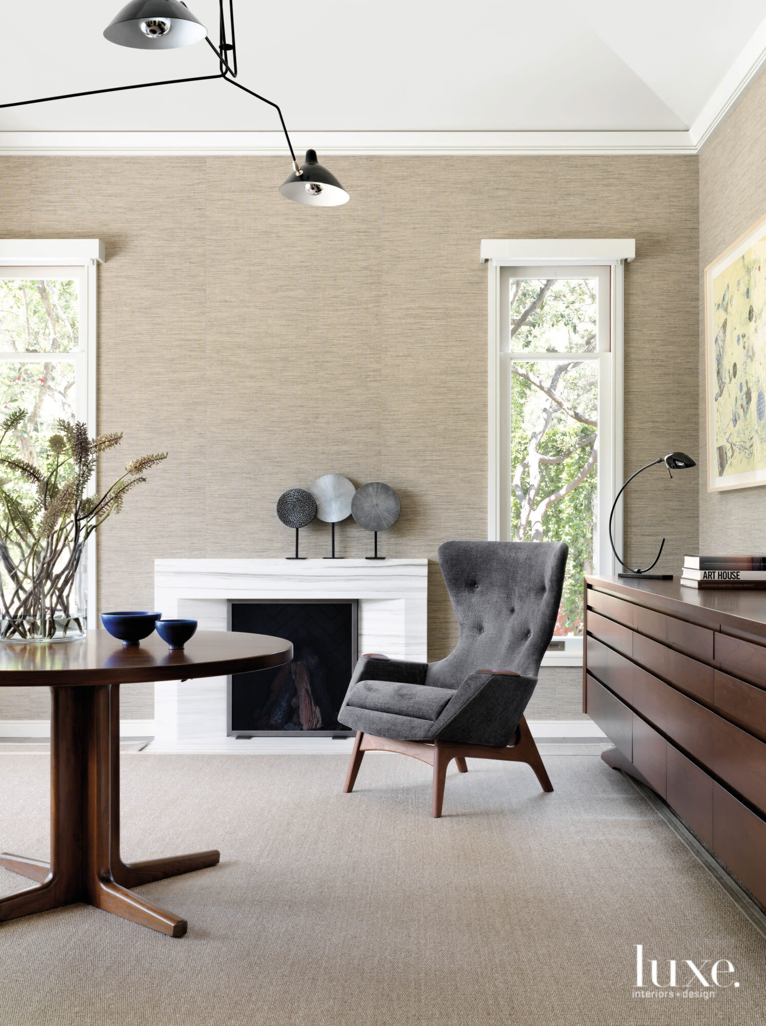 A study features a midcentury armchair and a fireplace.