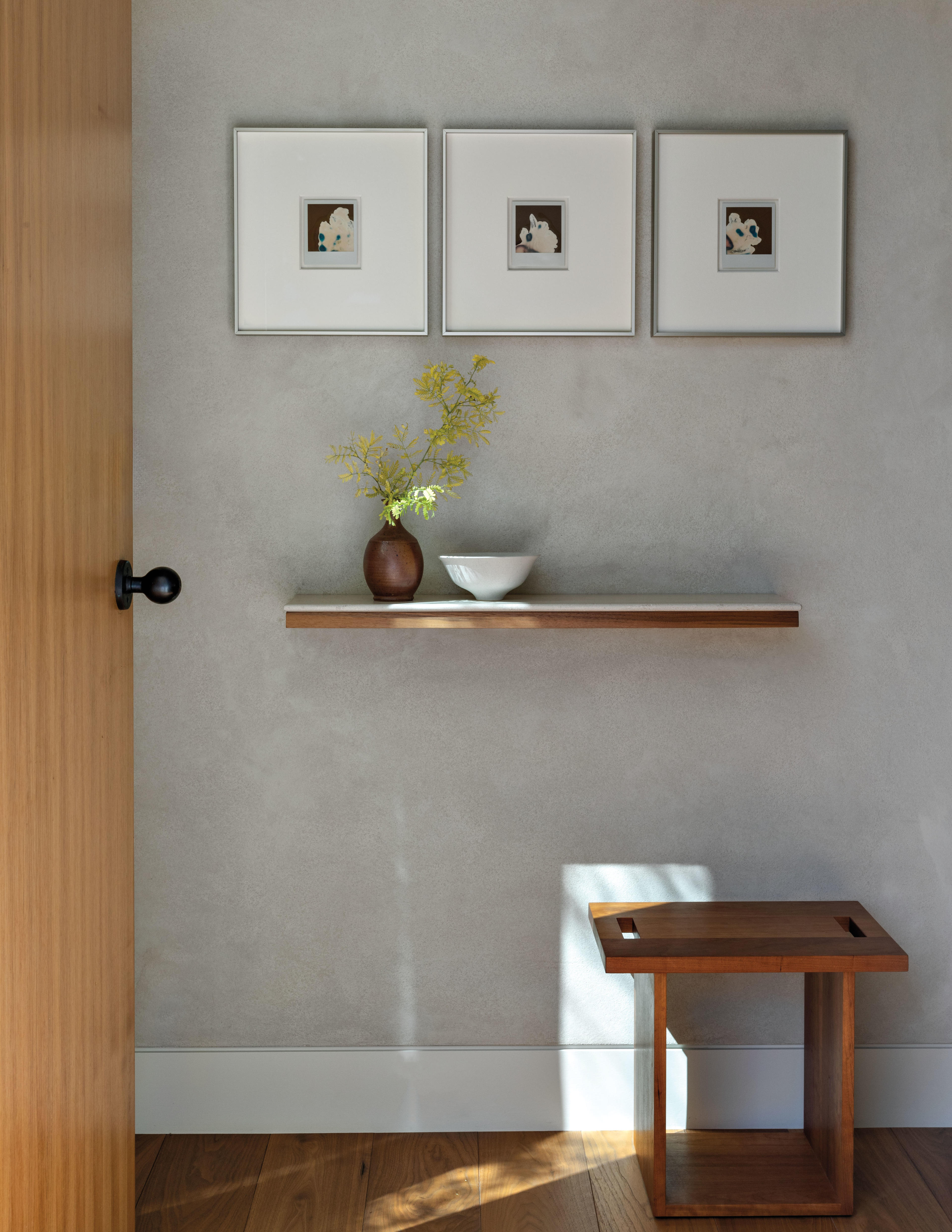 simple entry way with 3 square photos arranged above a floating shelf