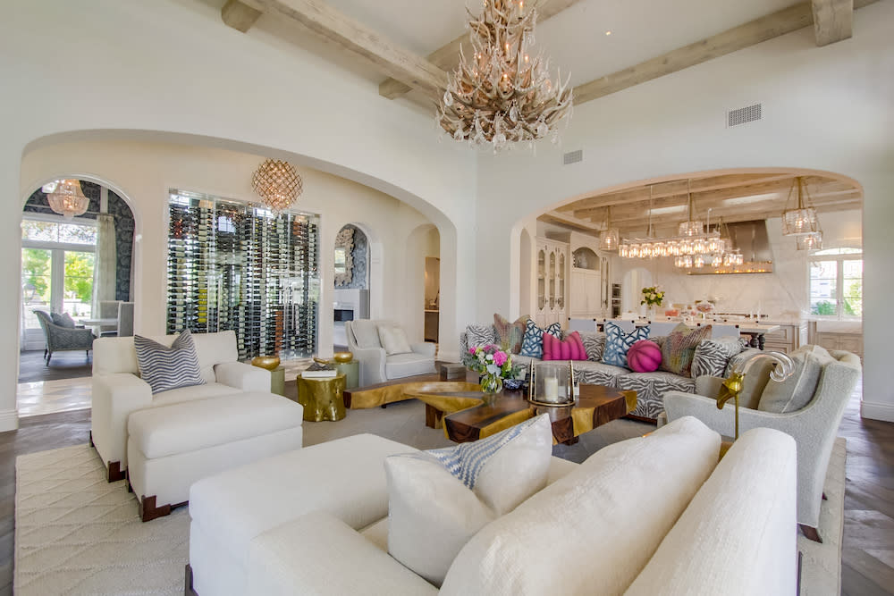 Elegant white couches, with pink pillows and gold chandelier, in a spacious living room