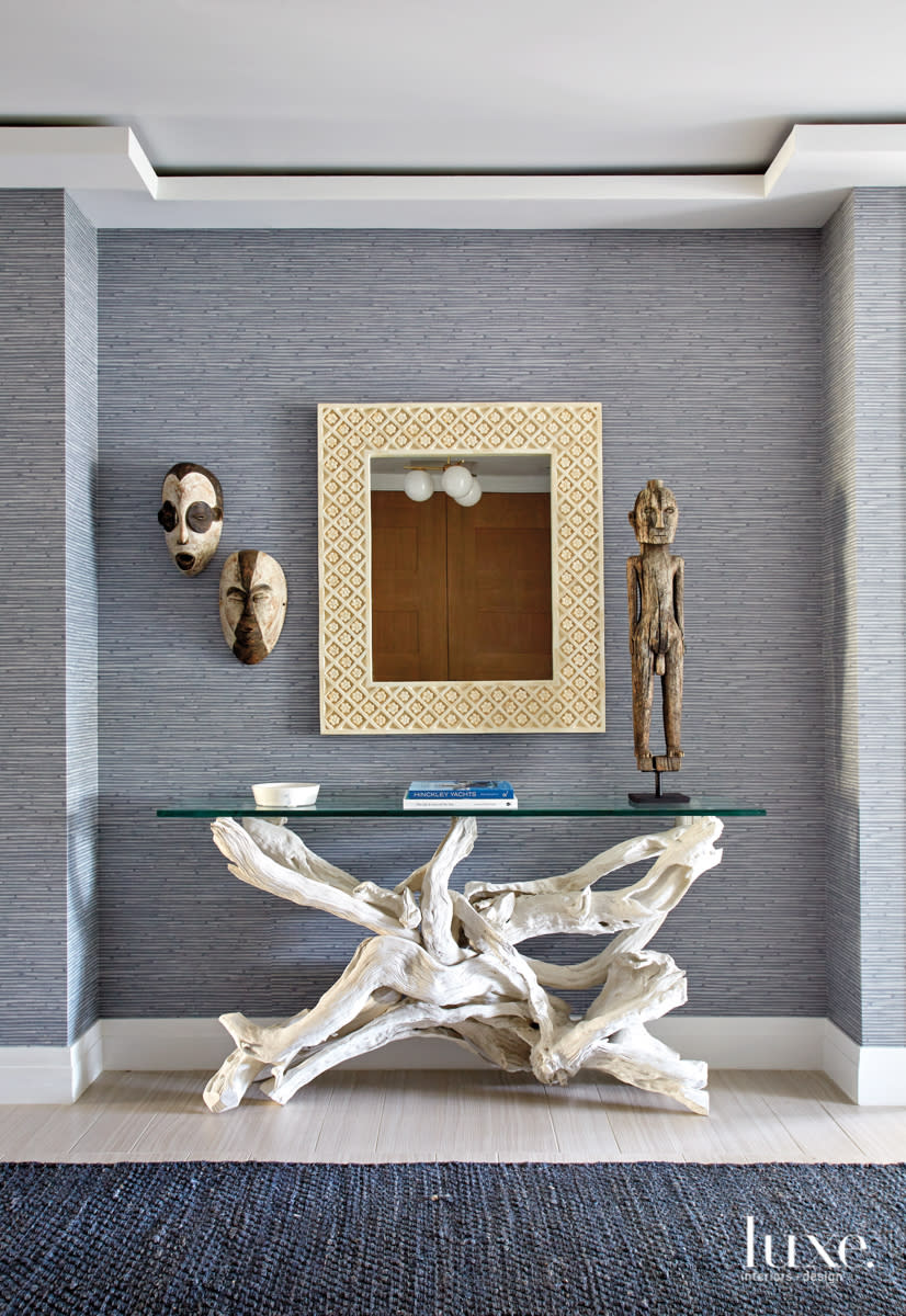 corridor with tribal masks and sculptures held up by a coral inspired table
