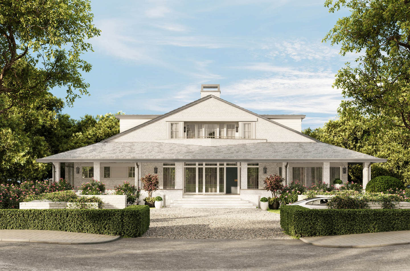 Classic white colonial-style house with a wrap-around porch, surrounded by lush greenery and flower bushes. The sky is clear, creating a serene atmosphere.
