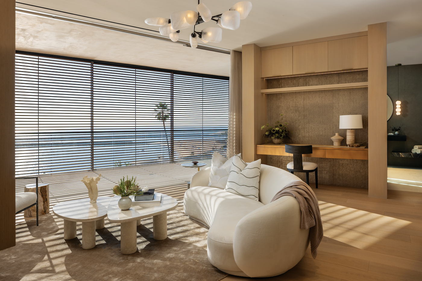 Primary suite sitting area opening to expansive Pacific Ocean views with soft, neutral furnishings