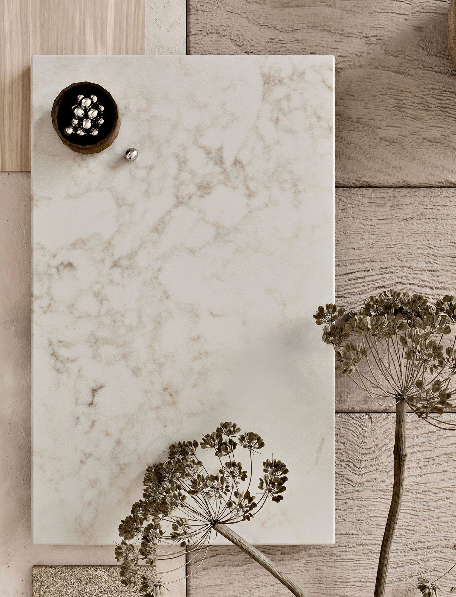 A rectangle of white quartz sits against a wood-paneled wall with dried plants in the foreground.