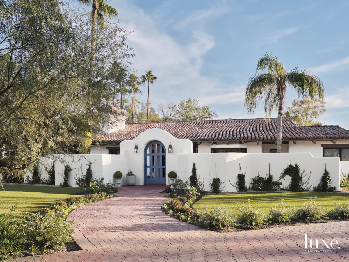 Bright greenery contrasts with the white exterior of the colonial-inspired home.