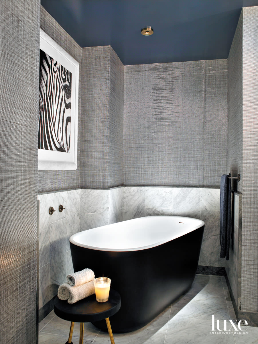 primary bathroom with freestanding tub, marble wall and silver wallcovering