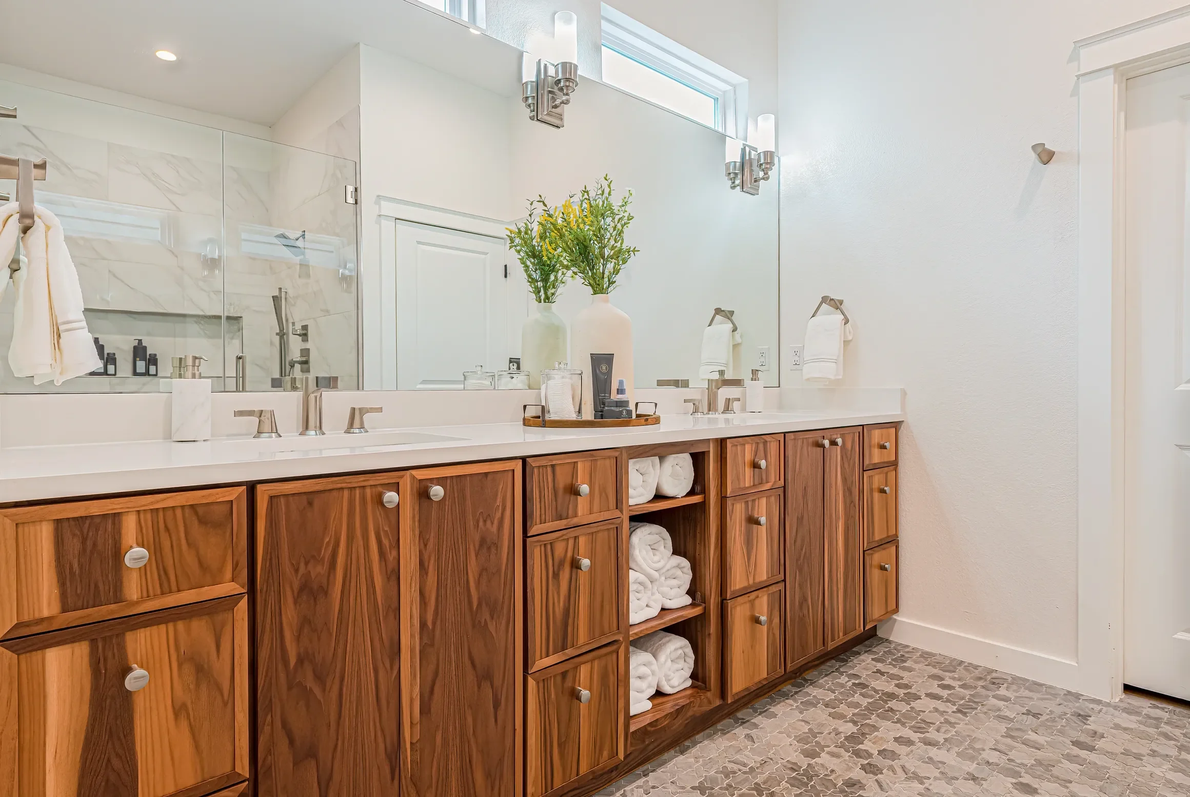 Warm wood vanity creates a relaxing atmosphere in this white bathroom. 