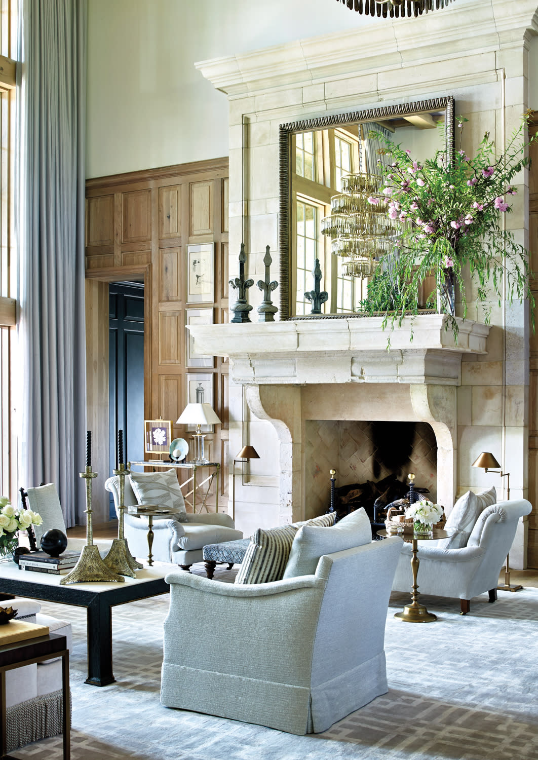 Double-height living room with large limestone fireplace and multiple seating groups