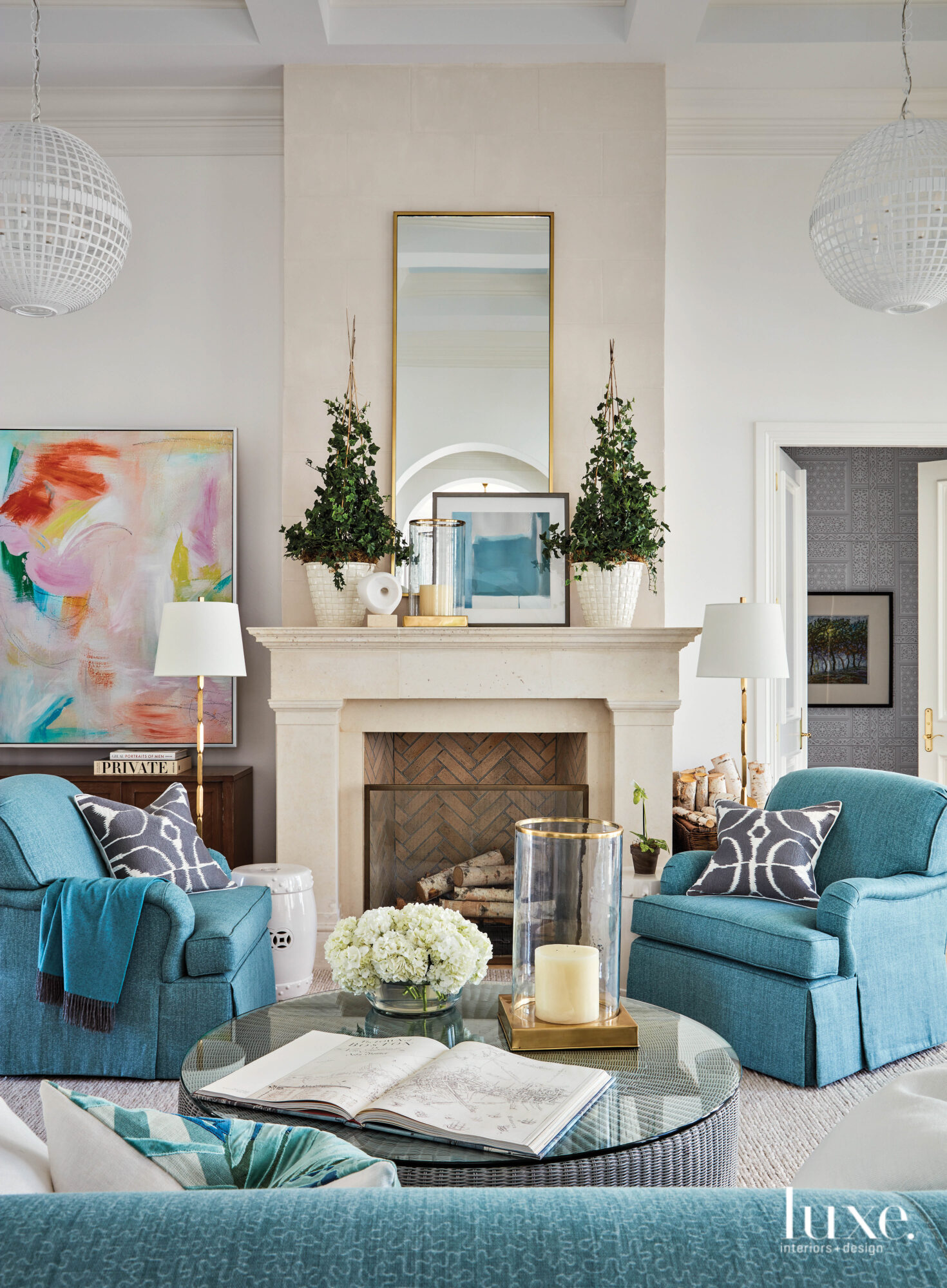 Living room with blue armchairs around a fireplace.