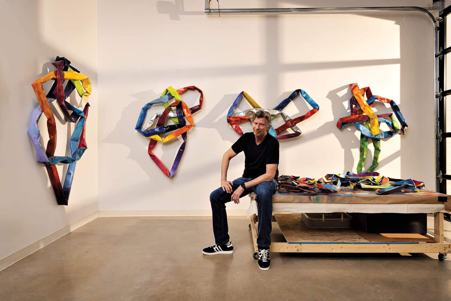 artist Tom Hoitsma in his studio with metal sculptures behind him