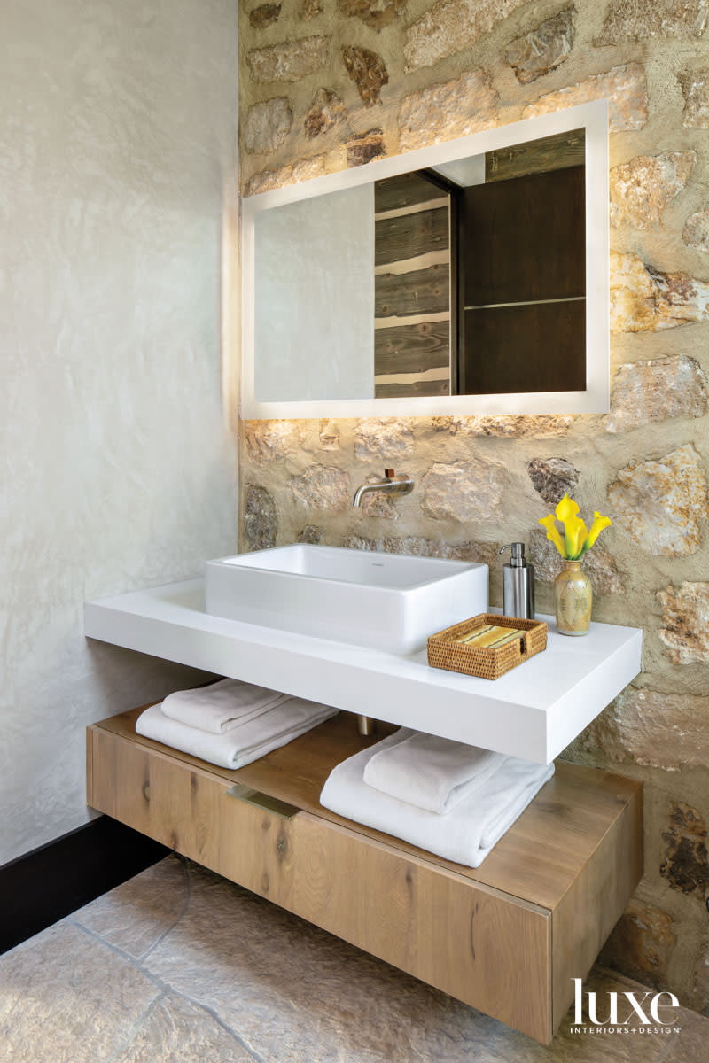 The powder room incorporates sleek elements against rustic walls.