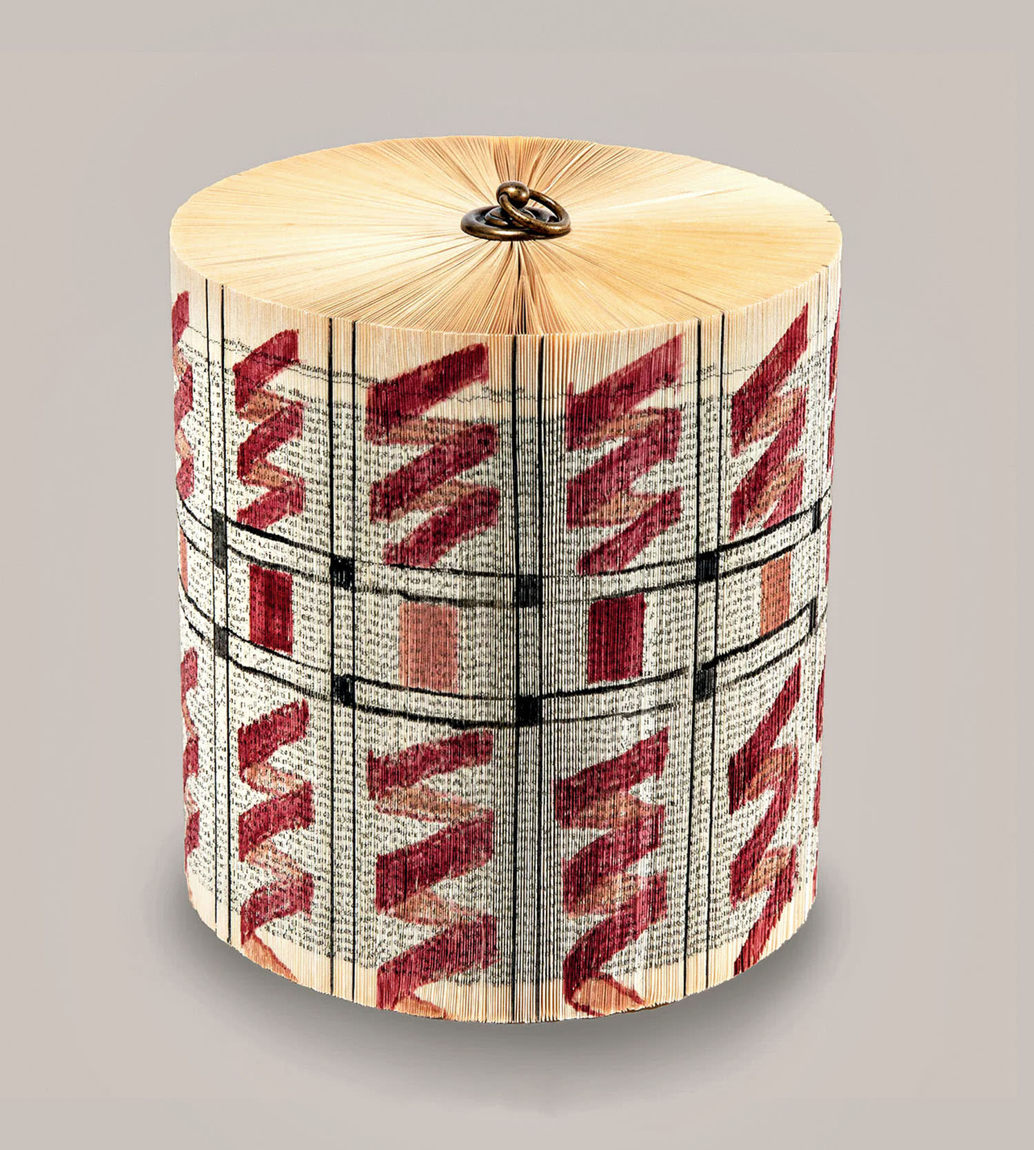 A hand-folded circular book sculpture with red accents.