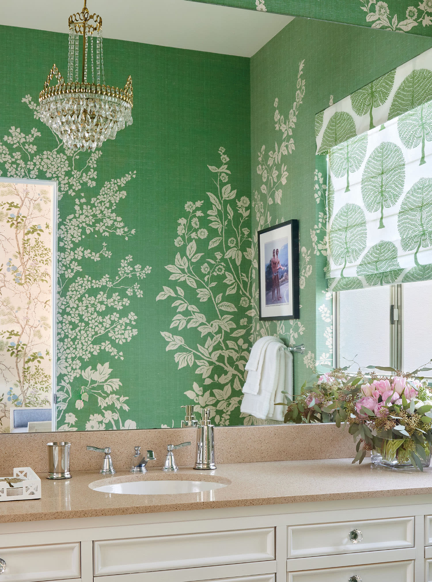 Elegant bathroom with white vanity, topped with lush flowers and a silver faucet.