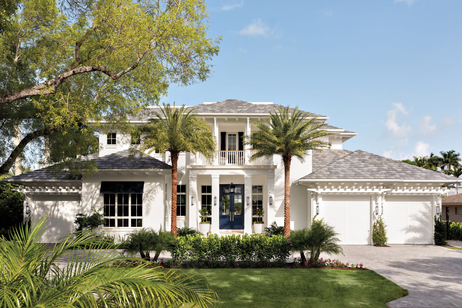 nautical, coastal-inspired exterior of a Naples home with black shutters and a blue door