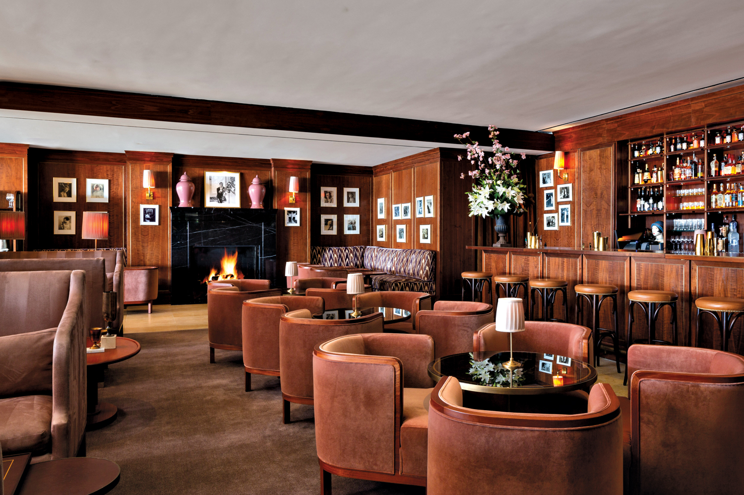 A restaurant with wood-panel walls and round velvet seats around low round tables