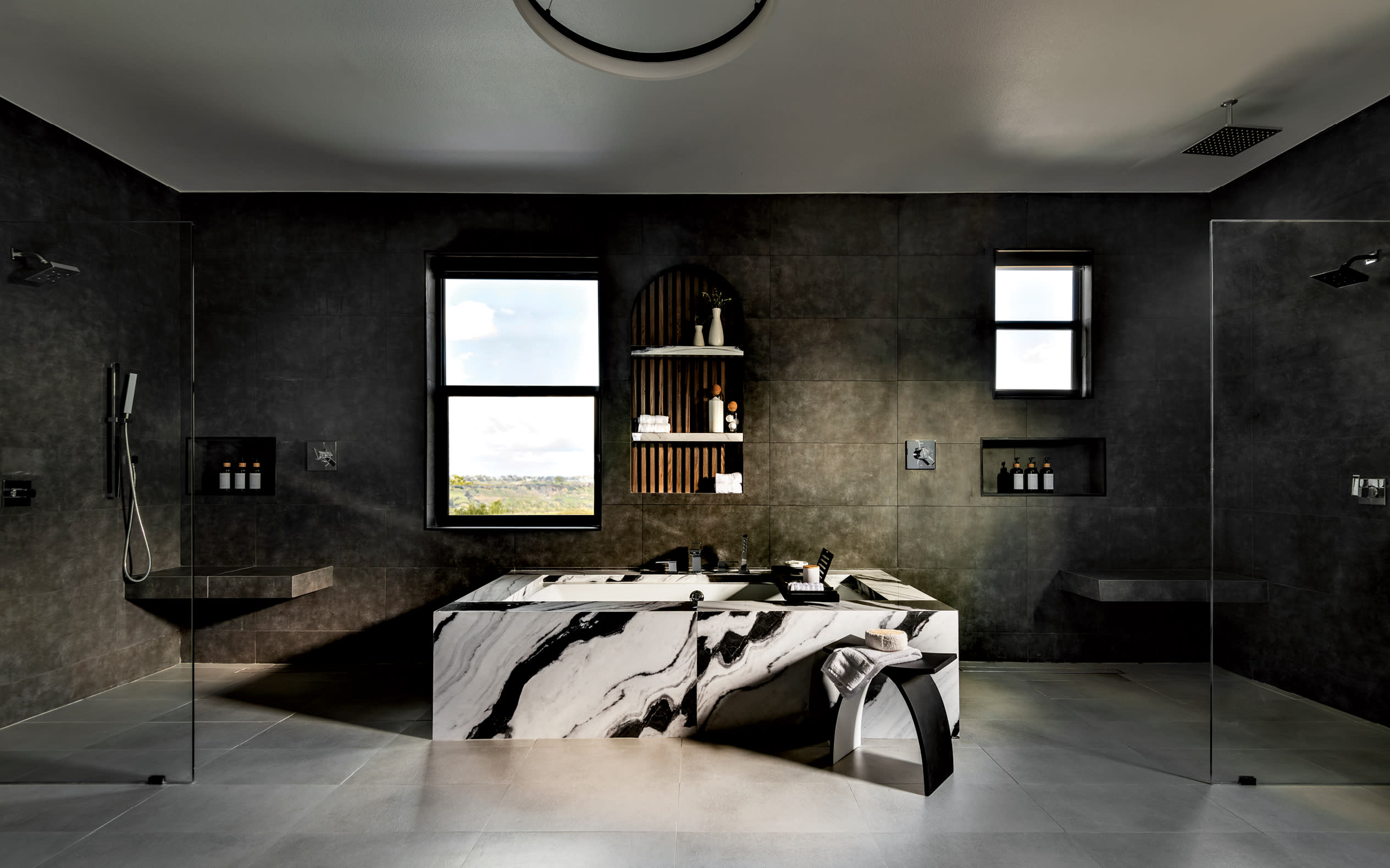 bathroom with a tub framed in dramatic black-and-white porcelain and set against dark wall tile