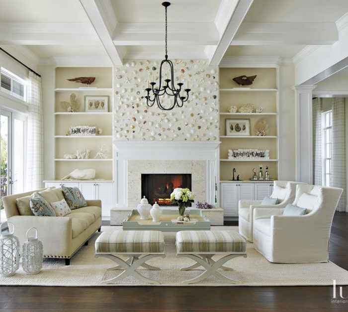 A rug from The Natural Carpet Company grounds the living room. A Lee Industries sofa and armchairs—from Pineapples, Palms, Etc.—join Hickory White benches in Kravet stripes around an Oomph coffee table. A Visual Comfort chandelier hangs above.