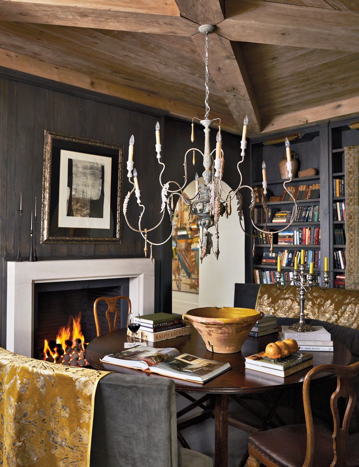 Dining room with dark wood paneling, a large chandelier and copious bookshelves