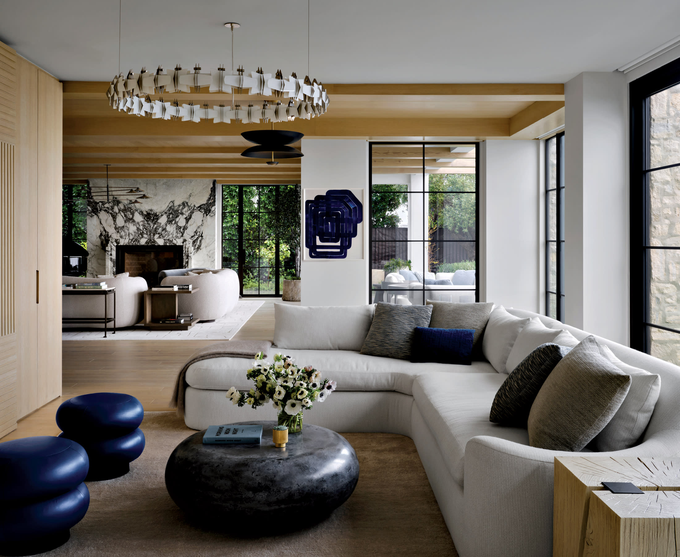 living room with a Lost Profile chandelier from Garde, gray sectional and blue ottomans