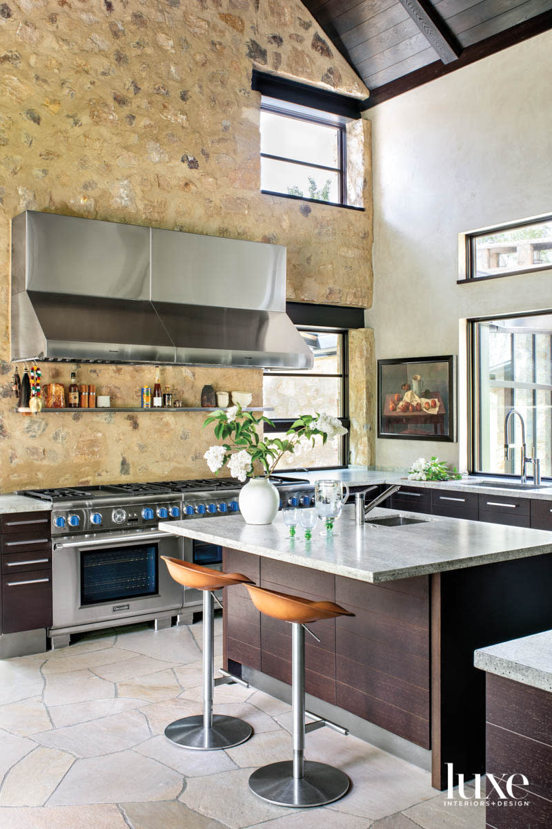 A large kitchen has stone wall and a large range.