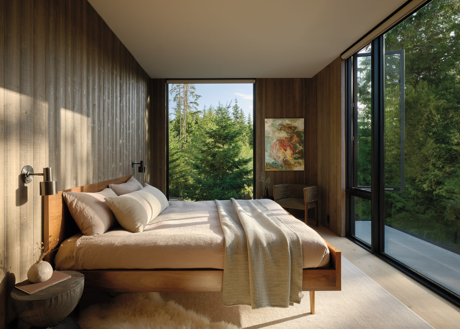 A cozy bedroom featuring a bed and a window with a view of a serene forest landscape.